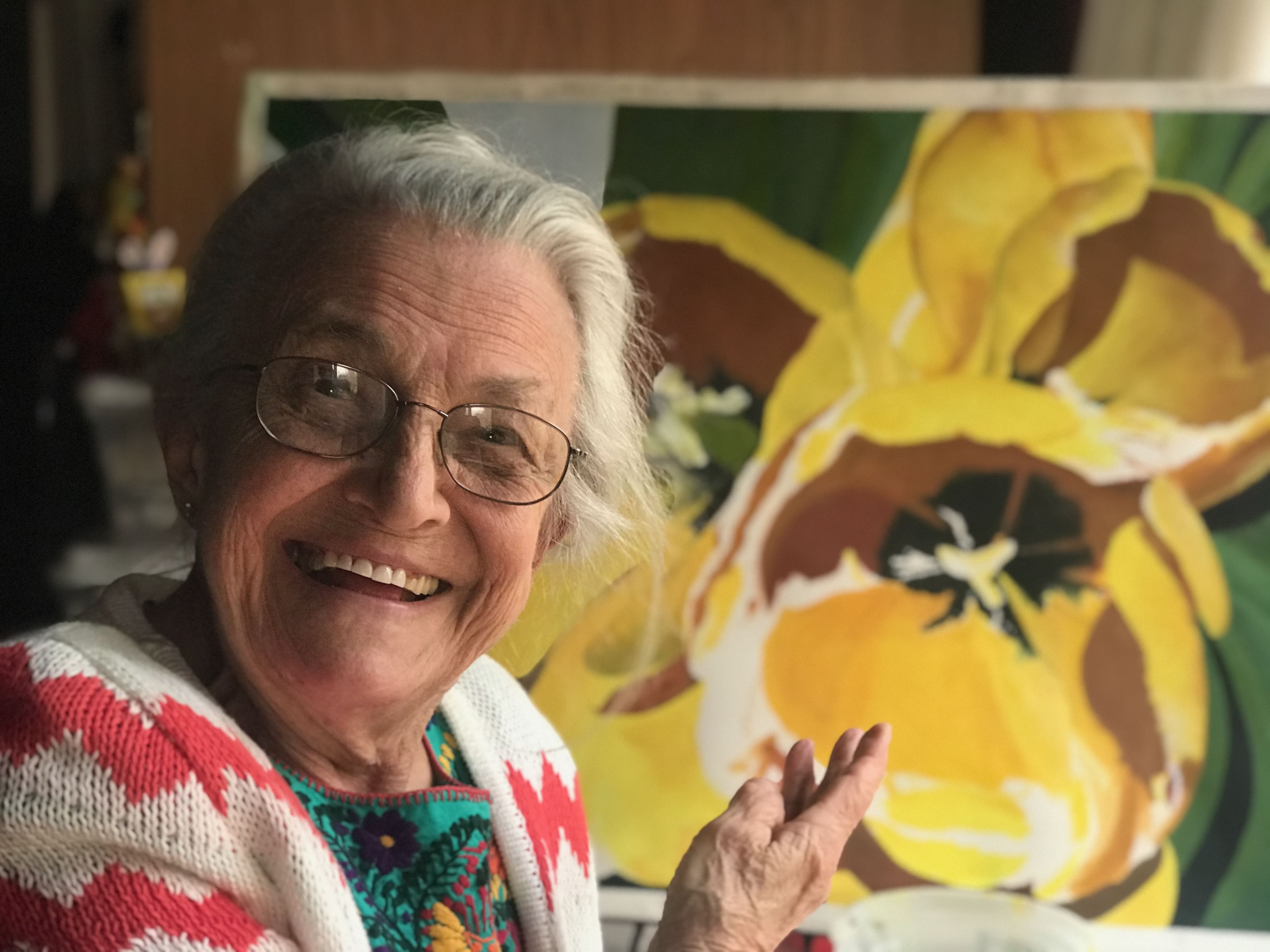 Victoria Chiofalo smiling beside a yellow flower painting